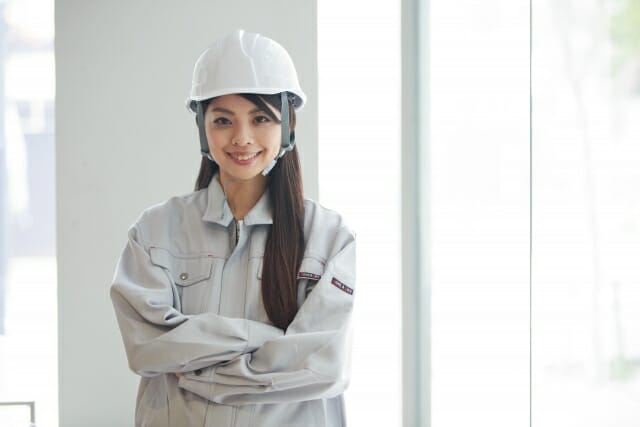 腕を組む作業員姿の女性